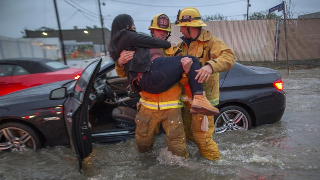 Des pompiers portent secours à une dame dont la voiture était coincée en raison d'une inondation à Sun Valley en Californie. Des pompiers portent secours à une dame dont la voiture était coincée en raison d'une inondation à Sun Valley en Californie.