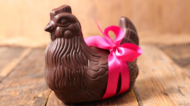 La poule en chocolat est entouré d'un ruban rose.