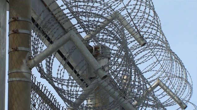 Barbelés sur le grillage du périmètre de sécurité d'une prison. Barbelés sur le grillage du périmètre de sécurité d'une prison.