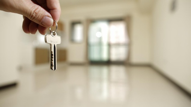 Une main tient une clé d'appartement