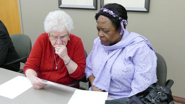 Deux femmes assises regardent atttentivement une feuille de papier. Deux femmes assises regardent atttentivement une feuille de papier.