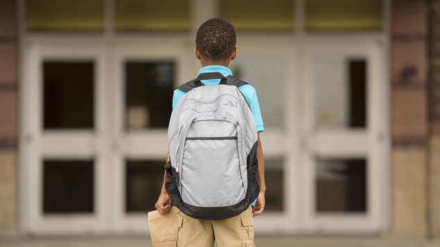 Un garçon afro-américain regarde les portes d'une école. Un garçon afro-américain regarde les portes d'une école.