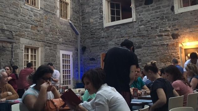 Des gens sont assis sur la terrasse d'un restaurant dans le Vieux-Montréal.