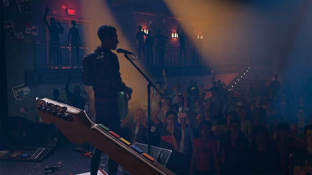 Un groupe de musique joue devant une foule dans une salle de concert et on voit les cinq boutons de couleurs traditionnels de Rock Band remplaçant les cordes sur le manche de guitare. Un groupe de musique joue devant une foule dans une salle de concert et on voit les cinq boutons de couleurs traditionnels de Rock Band remplaçant les cordes sur le manche de guitare.