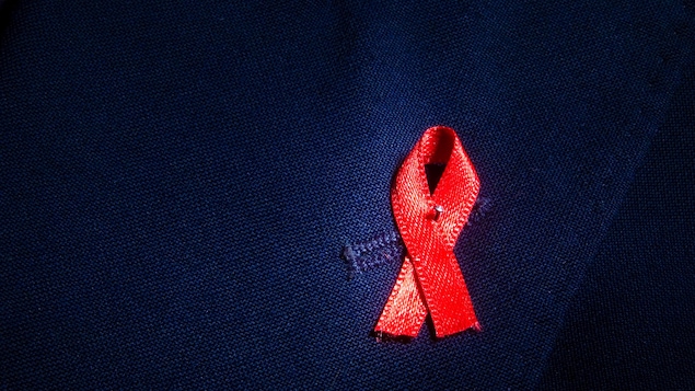 Un ruban rouge, symbole de la lutte au sida et au VIH, épinglé sur une veste.