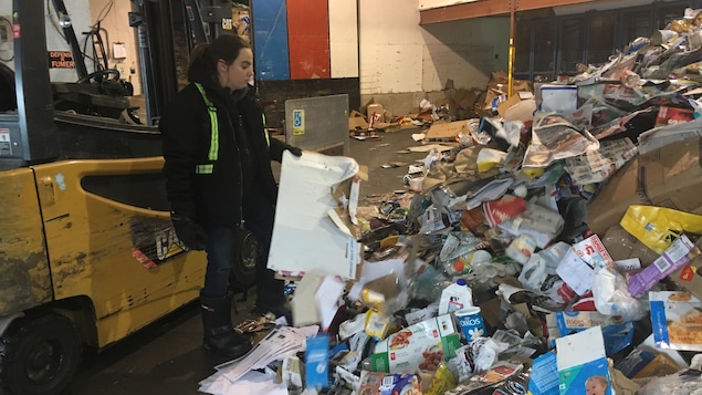 Une employée dans le centre de tri examine des déchets domestiques.