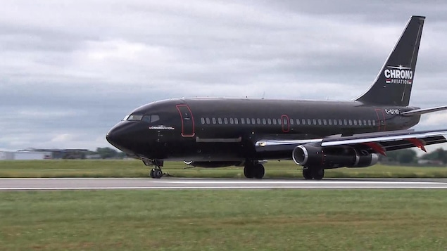 Un Boeing 737-200 de couleur noir roule sur la piste principale de l'aéroport de Saint-Hubert.