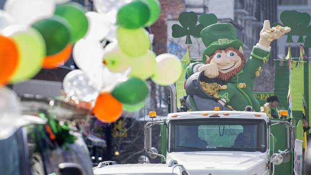 Un char allégorique avec un farfadet géant tenant un pot contenant des pièces d'or défile dans les rues de Montréal en 2017.