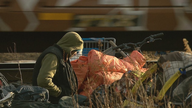 Un itinérant est assis au milieu d'un campement qui a été démoli près d'une voie ferrée à Moncton.