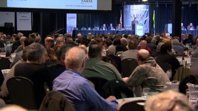 Un public assis écoute un conférencier qui s'adresse à lui dans une grande salle. Un public assis écoute un conférencier qui s'adresse à lui dans une grande salle.