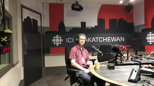 Un homme vêtu d'une chemise rouge et d'un jeans bleu dans les studios de Radio-Canada Regina