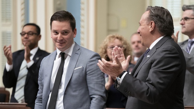 Simon Jolin-Barrette sourit debout en Chambre, l'air satisfait.