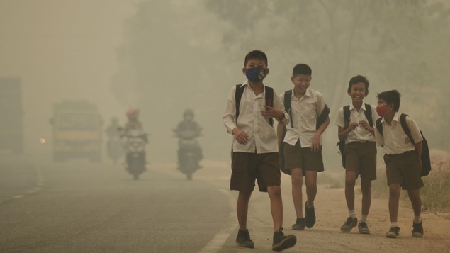 Des jeunes en Indonésie se rendent à pied à l'école malgré un smog épais. Des jeunes en Indonésie se rendent à pied à l'école malgré un smog épais.
