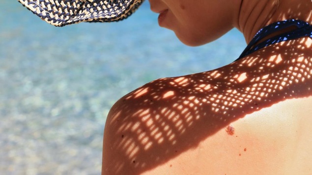Une femme au bord de la mer porte un chapeau