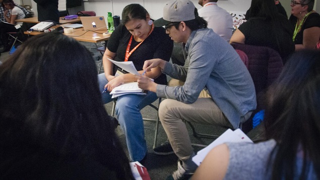Deux jeunes regardent des notes dans un cahier.