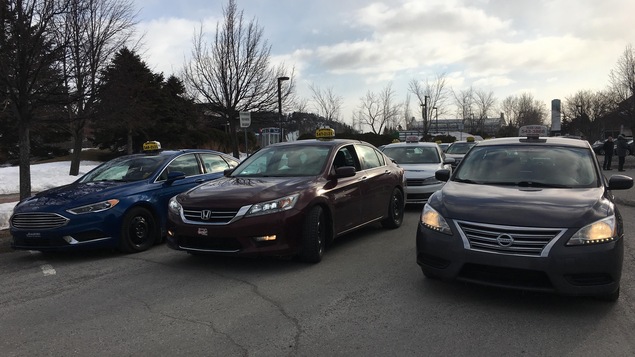 Trois voitures taxi stationnées une à côté de l'autre en attendant de commencer à circuler sur trois voies de circulation.