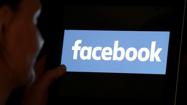 Une femme regardant le logo de Facebook sur une tablette électronique.