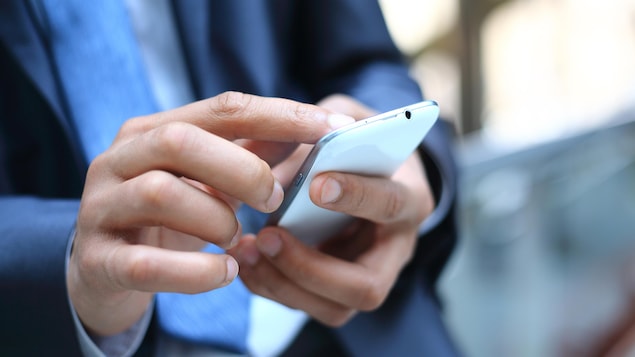 Un homme d'affaires manipule un téléphone intelligent.