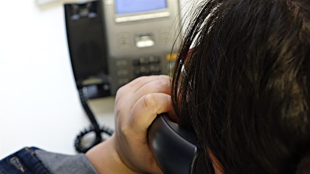 Une femme utilise un téléphone filaire à son bureau Une femme utilise un téléphone filaire à son bureau