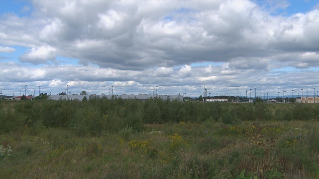 On voit un terrain plat et à l'arrière, il y a le bâtiment de l'ancien Walmart.