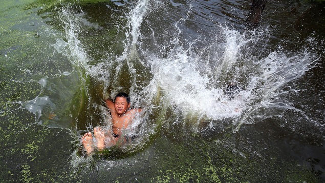 Un garçon saute dans l'eau froide du village Chuong à l'extérieur d'Hanoï au Vietnam. Un garçon saute dans l'eau froide du village Chuong à l'extérieur d'Hanoï au Vietnam.