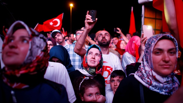 Des femmes, des hommes et des enfants semblent regarder au loin. Des drapeaux de la Turquie flottent autour d'eux. Des femmes, des hommes et des enfants semblent regarder au loin. Des drapeaux de la Turquie flottent autour d'eux.