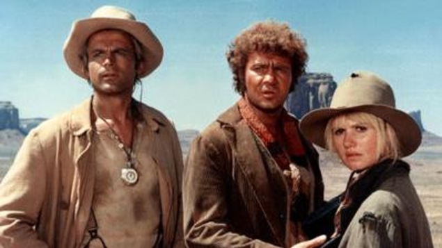 Les trois personnes sont dans le désert et paraissent surprises.