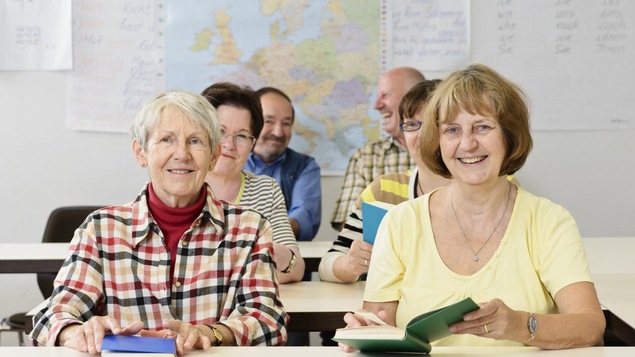 Des femmes sont assises avec un livre à la main dans une salle de classe.