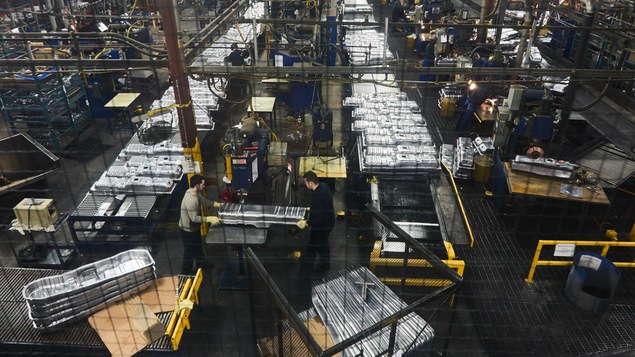 Vue de haut, à travers un grillage, d'employés qui travaillent à l'usine Spectra Premium de Boucherville. Vue de haut, à travers un grillage, d'employés qui travaillent à l'usine Spectra Premium de Boucherville.