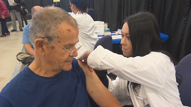 Une infirmière administre à un homme un vaccin contre le grippe.