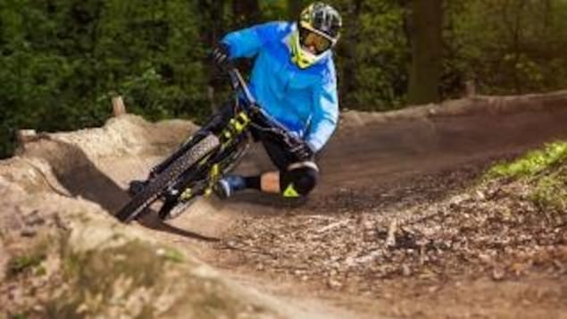 Un cycliste de montagne prend une courbe dans un sentier en forêt.
