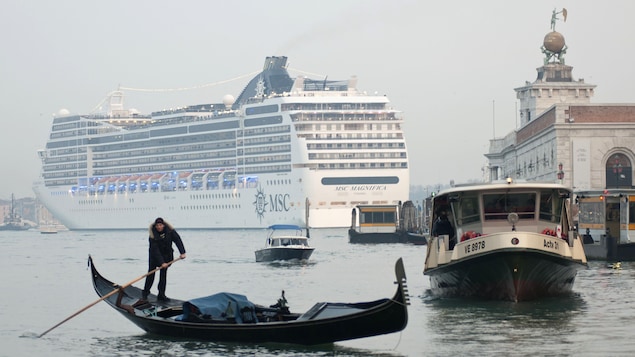 Un navire de croisière dans le Grand canal de Venise, devant un batelier sur sa petite embarcation.