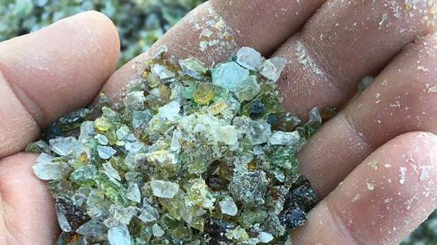 Main avec du verre recyclé.