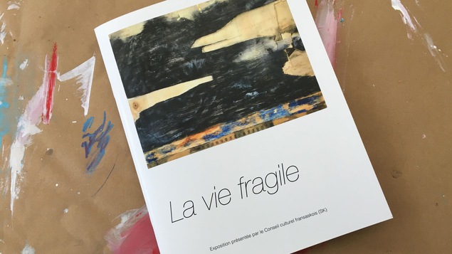 Un catalogue déposé sur du papier brun taché de peinture