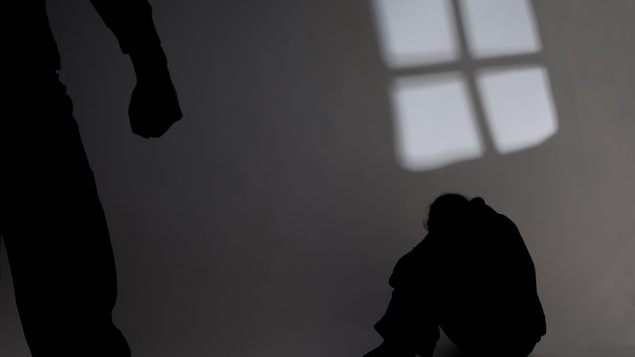 Une personne est assise par terre et une autre personne au premier plan a le poing serré.