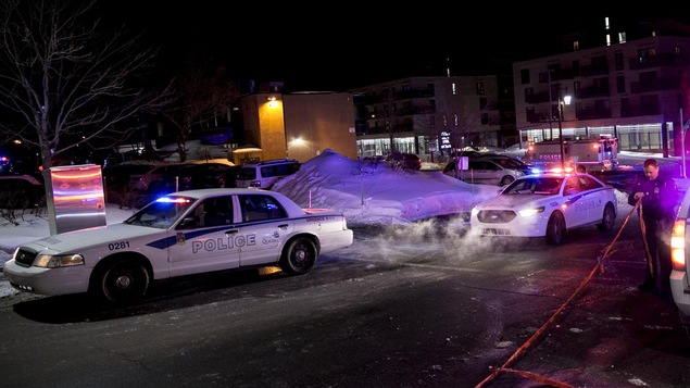 Des voitures du SPVQ stationnées aux abords du Centre culturel islamique de Québec le 29 janvier 2017. Un policier met en place un périmètre de sécurité à l’aide d’un ruban rouge.