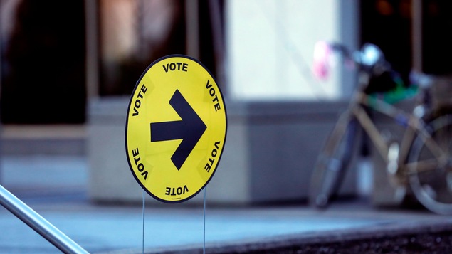 Une flèche indique l'entrée du bureau de vote