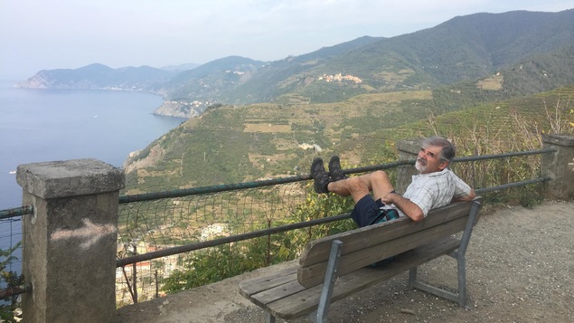 Normand Simard assis sur un banc devant les villages des Cinque Terre