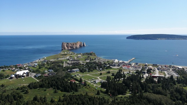 Vue en plongée sur un village, le Rocher Percé et l'île Bonaventure.