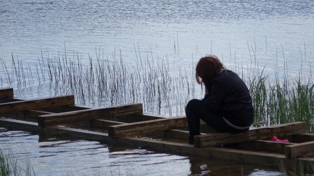 Une adolescente est assise sur un quai