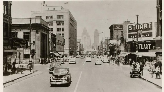 Une rue achanlandée, des automobiles circulent. Au loin, on aperçoit les gratte-ciel de Détroit. Une rue achanlandée, des automobiles circulent. Au loin, on aperçoit les gratte-ciel de Détroit.