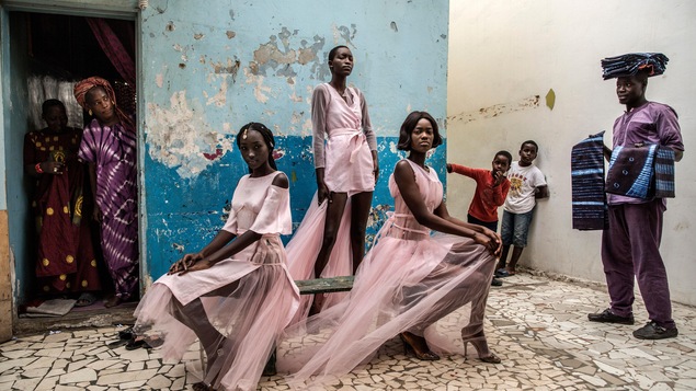 Trois femmes portent les tenues de la créatrice Adama Paris, dans le quartier de la Médina de Dakar, la capitale sénégalaise, sous le regard des habitants.
