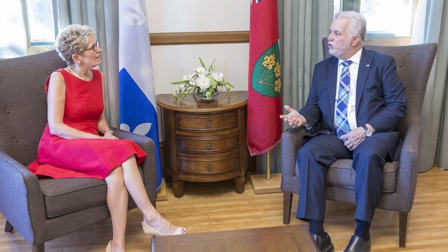 Photo de Kathleen Wynne et de Philippe Couillard qui discutent assis dans des fauteuils.