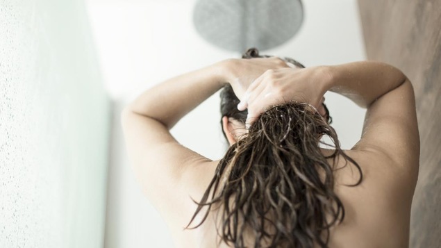 Une femme a les cheveux humides sous la douche.