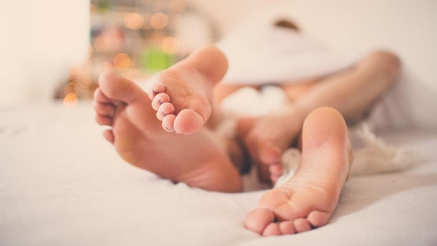 Un plan rapproché des pieds d'un homme et d'une femme entremêlés dans un lit.