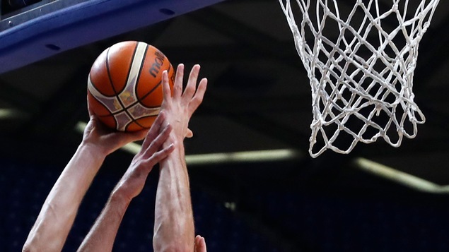 Trois bras sont dans les airs afin de capter un ballon de basketball