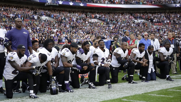 Des joueurs des Ravens de Baltimore et leur ancien coéquipier Ray Lewis (deuxième à partir de la droite) s'agenouillent au cours de l'interprétation de l'hymne national américain.