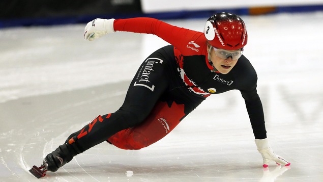 La patineuse Kim Boutin, vêtue d'une combinaison rouge et noire, pose la main sur la glace lors d'un virage d'une course de patinage de vitesse sur courte piste à Salt Lake City.