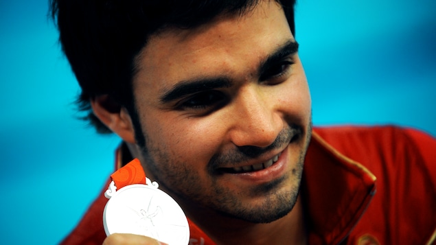 Alexandre Despatie montre fièrement sa médaille en souriant.