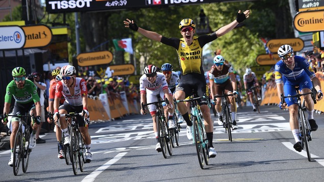 Wout van Aert célèbre sa victoire en levant les bras en l'air.